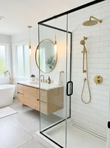Black framed glass shower with white tiles and gold fixtures