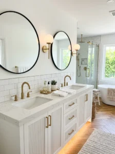 White double bathroom sink vanity with gold faucets and black mirrors
