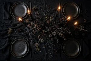 Moody Halloween dinner table lit by tall black taper candles with dark elegant table setting